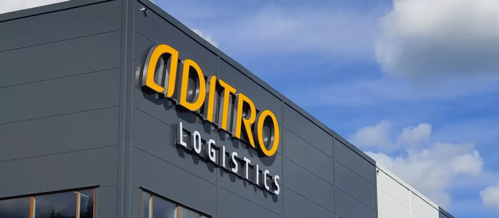 Fasadskylt med belysta profilbokstäver, Aditro Logistics, på en industribyggnad